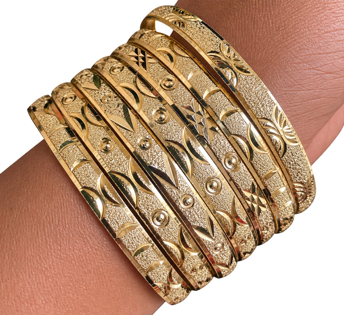 Close-up of Stack Haus diamond-cut gold bangles on wrist against white background